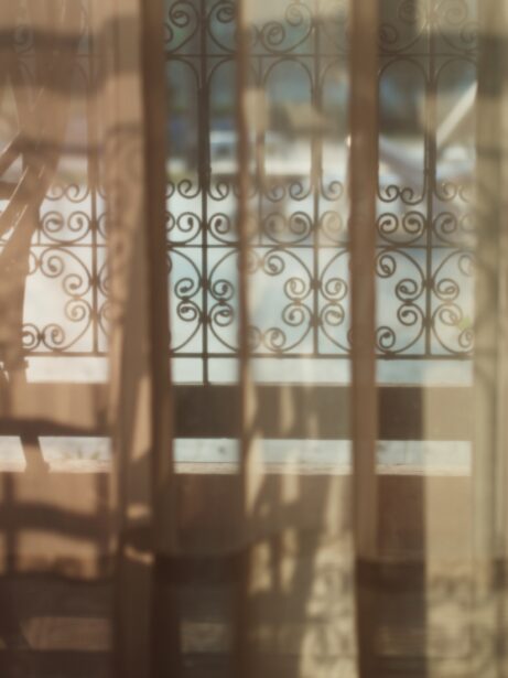světlo prosvítající záclonou, tepané zábradlí
